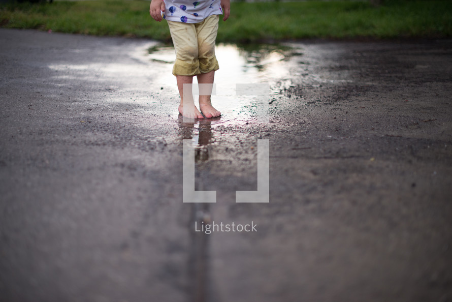 Child's feet standing in a puddle after the rain.