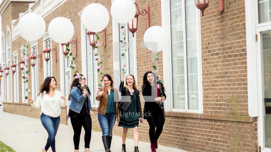 women walking down the sidewalk with balloons