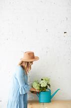 woman arranging a watering can with hydrangeas 