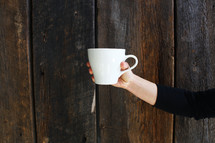 outstretched arm holding out a coffee cup 