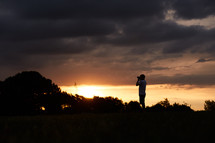 silhouette of a man with a camera taking pictures at sunset 