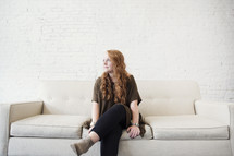 a young woman sitting on a couch thinking 