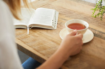 a woman with a tea cup reading a Bible 