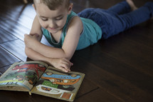  a toddler boy reading a book on the floor 