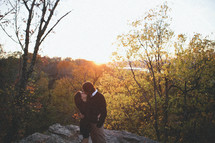 husband and wife kissing outdoors in the woods