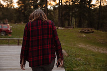 a woman in a flannel shirt walking on a deck 