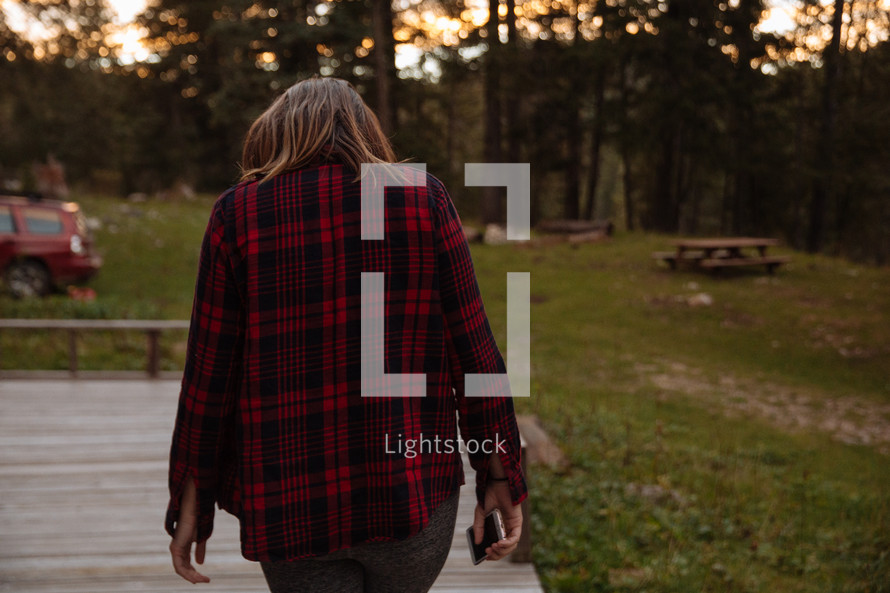 a woman in a flannel shirt walking on a deck 