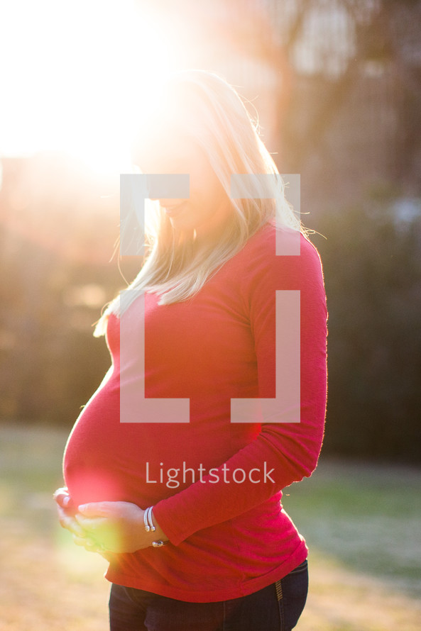 portrait of a pregnant woman standing in sunlight 
