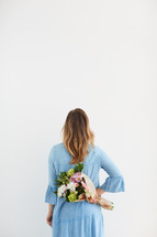 a woman holding a bouquet of flowers behind her back 