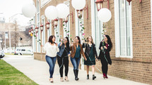 women walking down a sidewalk with balloons 