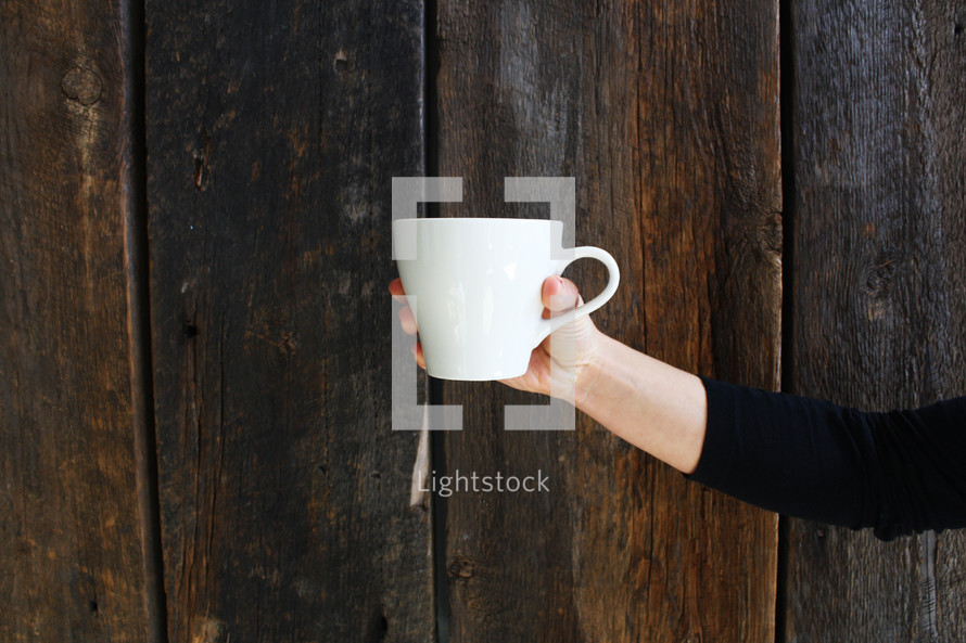 outstretched arm holding out a coffee cup 