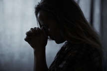 a woman praying in darkness 