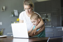 a mother teaching her son to use a computer 