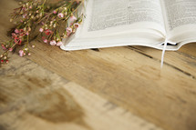 open Bible and flowers on a wood table 