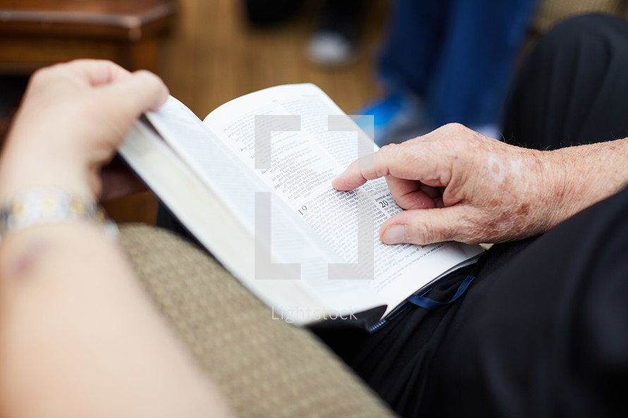 elderly man reading a Bible in his lap 
