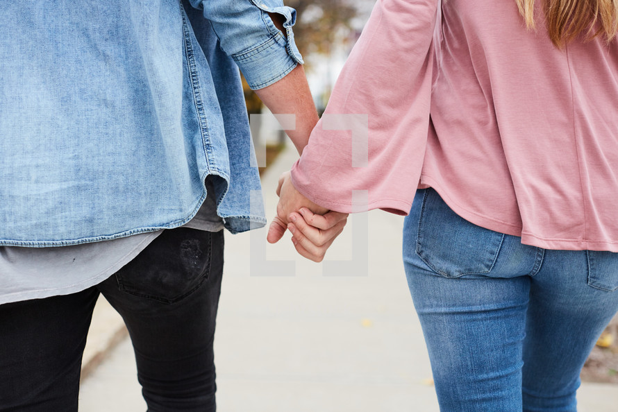 close up of a couple walking on a sidewalk holding hands 