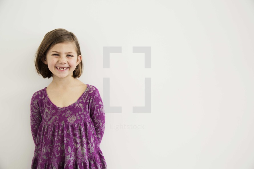 portrait of smiling young girl against white wall.