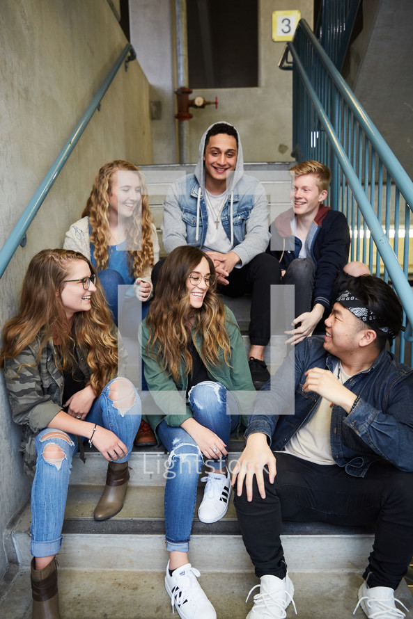 group of teens talking sitting on steps 