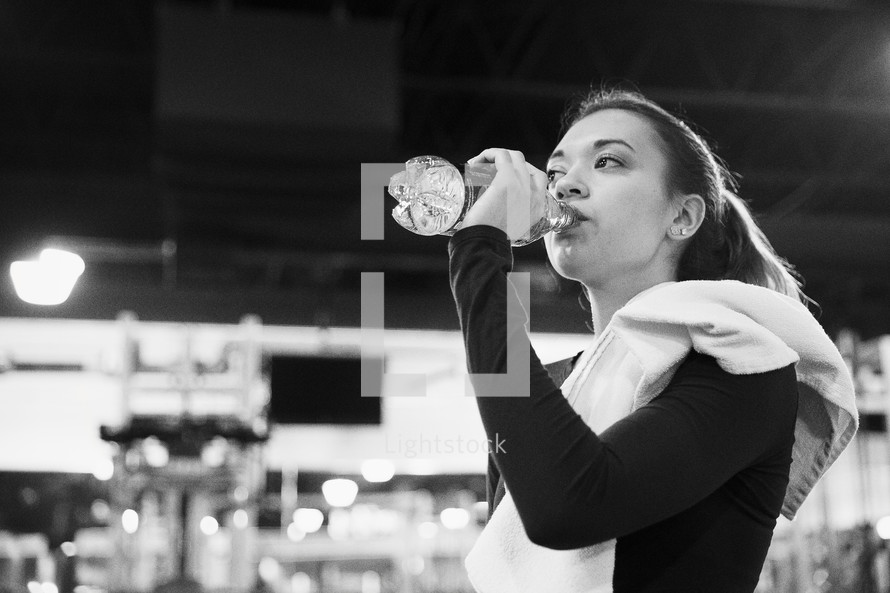 a woman drinking water in the gym