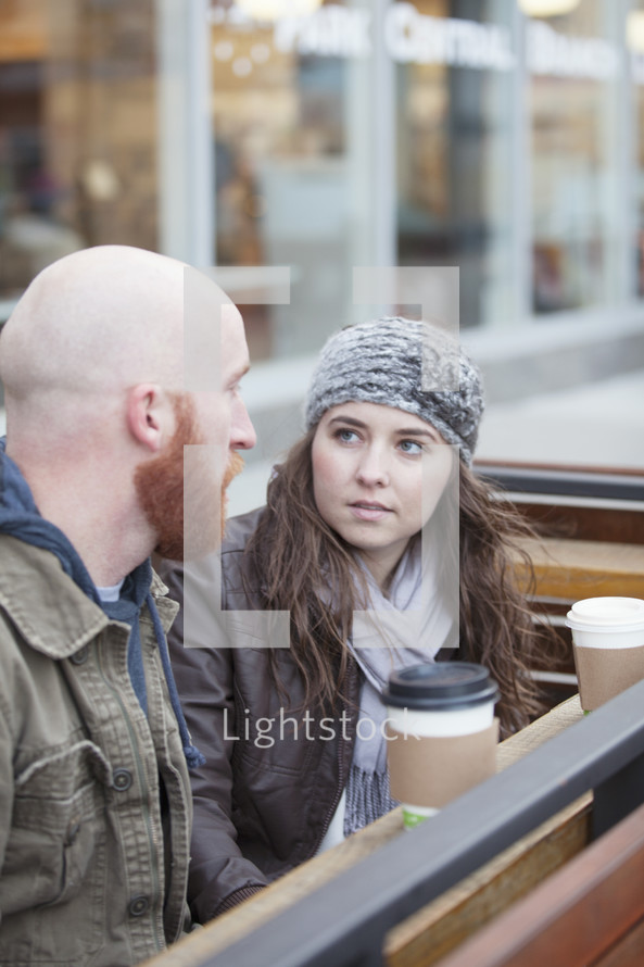 Couple sitting outside with coffee having a serious conversation.