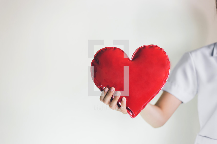 a healthcare worker holding a heart 
