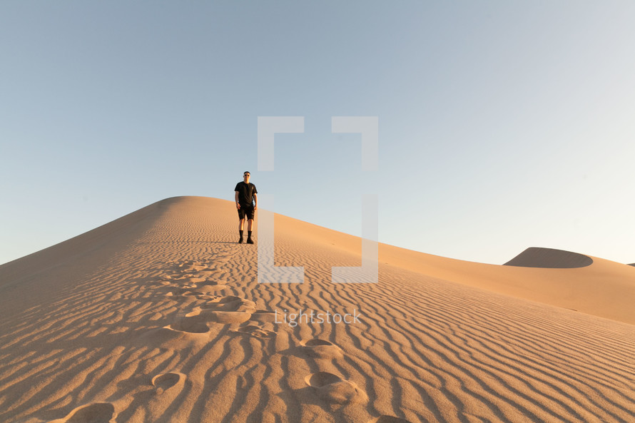 a man standing on desert sand dunes 