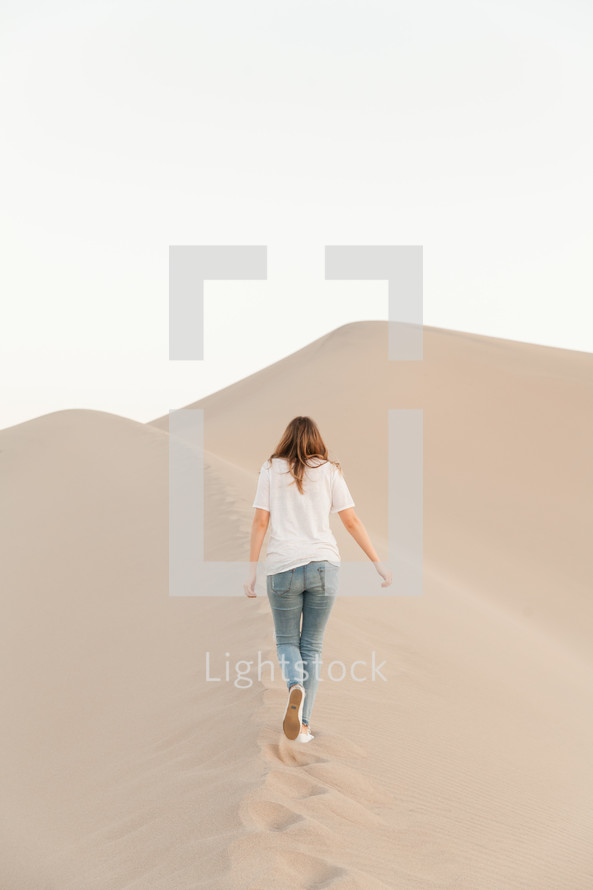 a woman standing on desert sand dunes 
