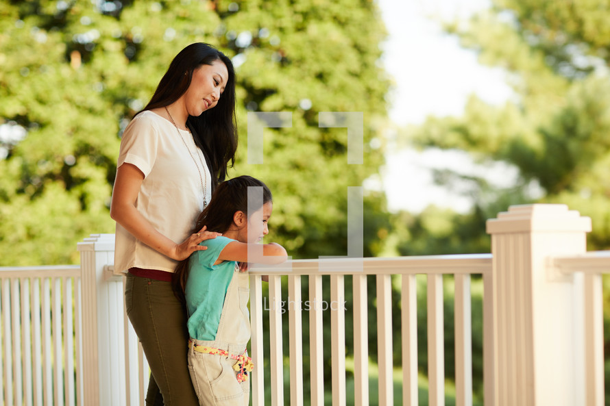 a woman standing on a back porch with her daughter 