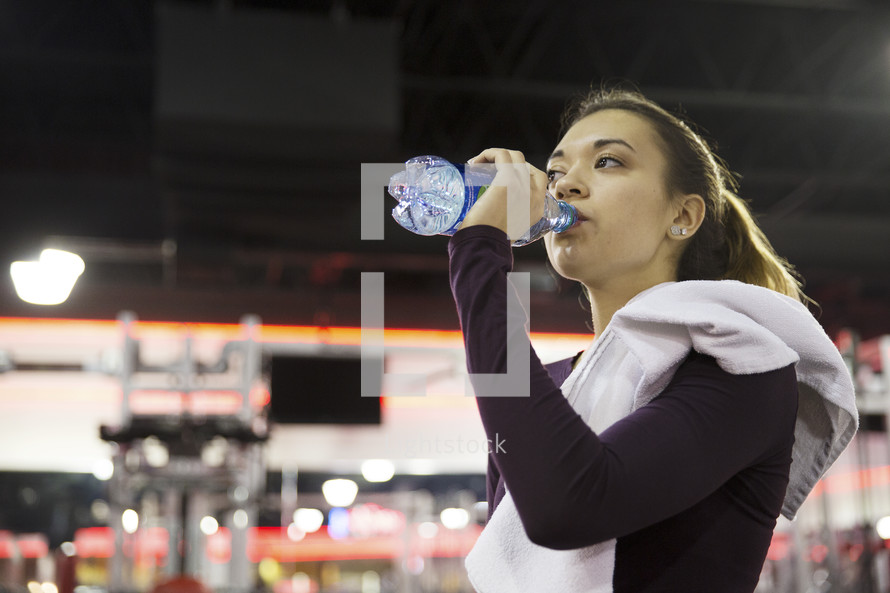 a woman drinking a water bottle in the gym 