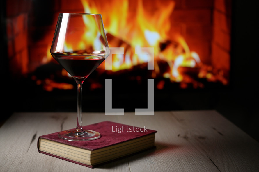 	Dry Glass Of Red Wine, on Book and Fireplace in Background