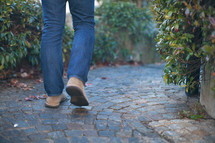 man walking on a cobblestone path