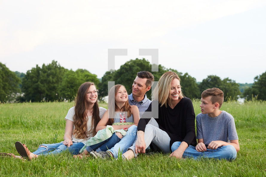 a portrait of a family sitting in spring grass