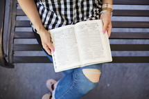 a woman sitting on a porch swing reading a Bible 