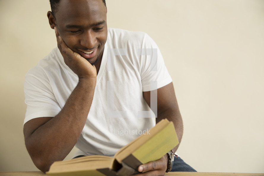 an African American man reading a book at a desk.