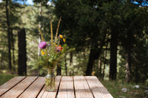 flowers in a vase on a picnic table 
