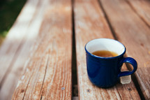 tea in a mug on a picnic table 