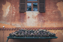 gutters, tile roof, and exterior wall with a window 