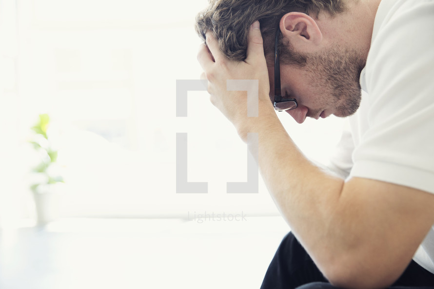a stressed man holding his head down.