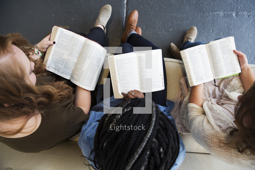 a young women sitting on a couch reading a Bibles 