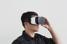 A young man looking through virtual reality glasses.
