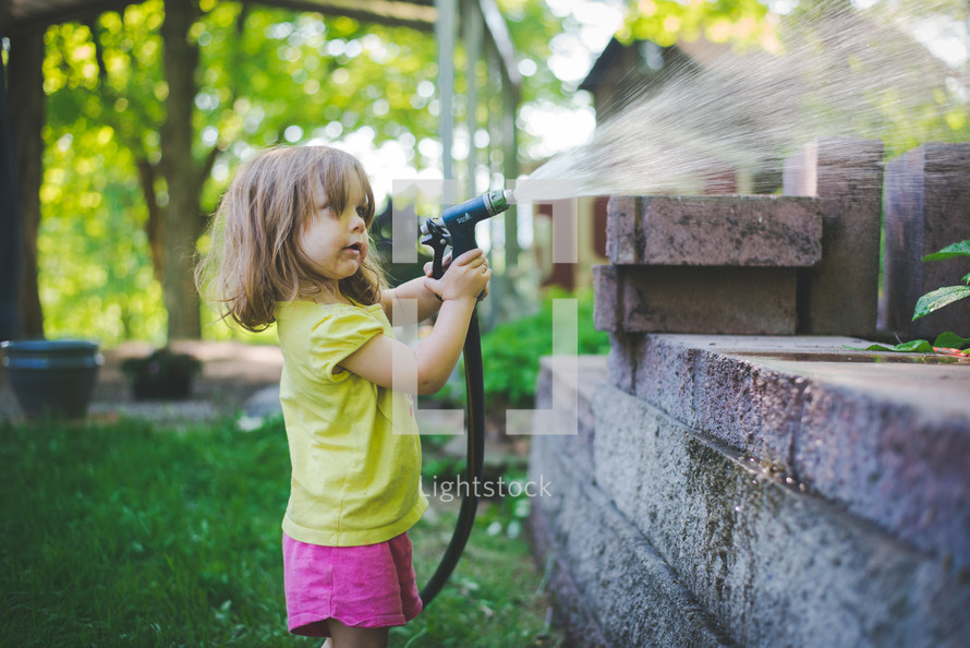 a little girl spraying a water hose 