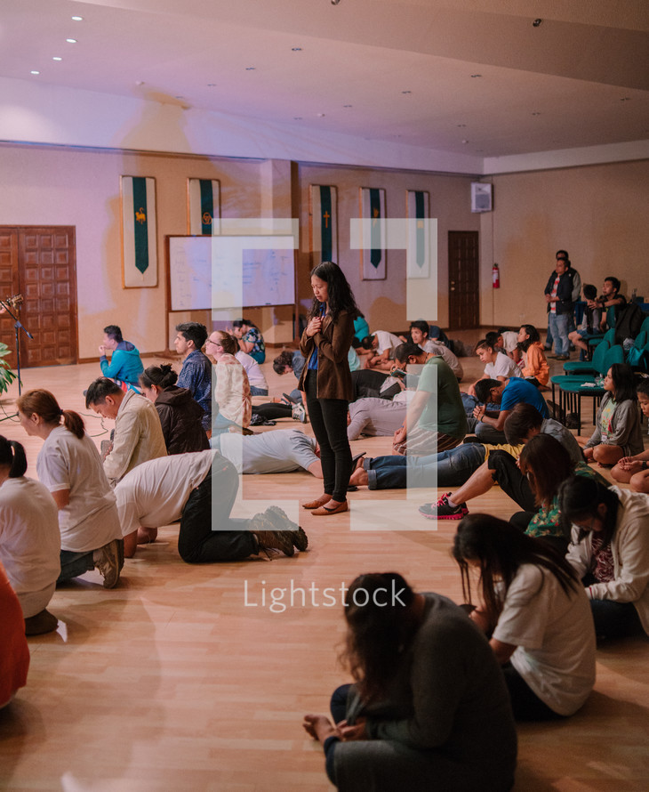teens sitting on a floor praying during a worship service 