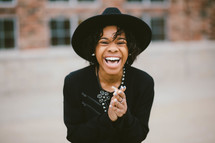 An African American woman in a black hat laughing 