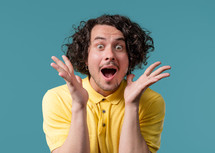 Shocked curly haired man glad, he screaming WOW. Impressed guy trying to get attention. Concept of summer sale, profitable offer. Excited happy on blue background. High quality