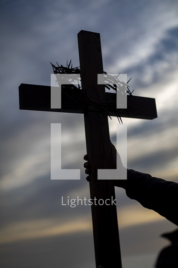 silhouette of a man holding a cross at sunset 