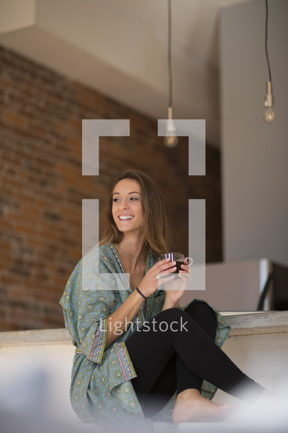 a woman in her robe and pajamas with a cup of coffee