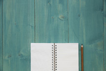 teal blue background and blank pages of a notebook 