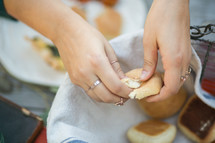 a woman breaking a bread roll 