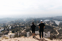 two men looking down at a valley city 