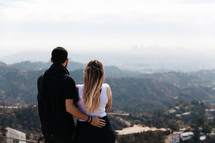 a couple looking out over suburbs in a valley 